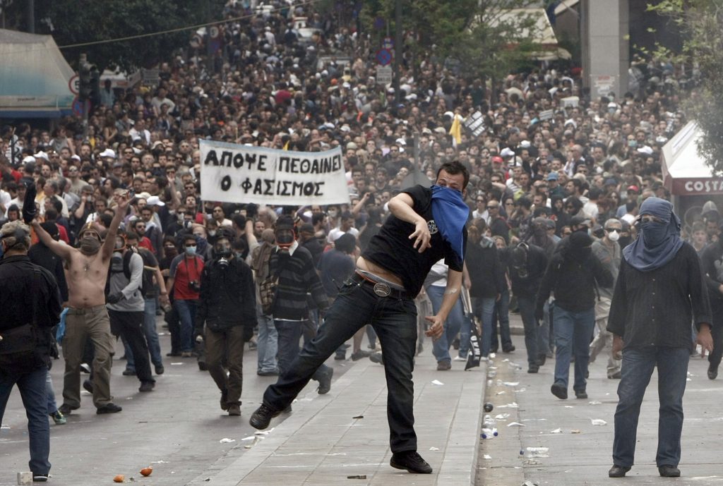 Demonstartors hurl projectiles at riot police near the Greek parliament in Athens during a nationwide strike in Greece, May 5, 2010.  Greece braced for a day of demonstrations during a nationwide strike by civil servants protesting the announcement of draconian austeristy measures.       REUTERS/John Kolesidis (GREECE)